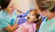 Осмотр маленькой пациентки в кресле у стоматолога