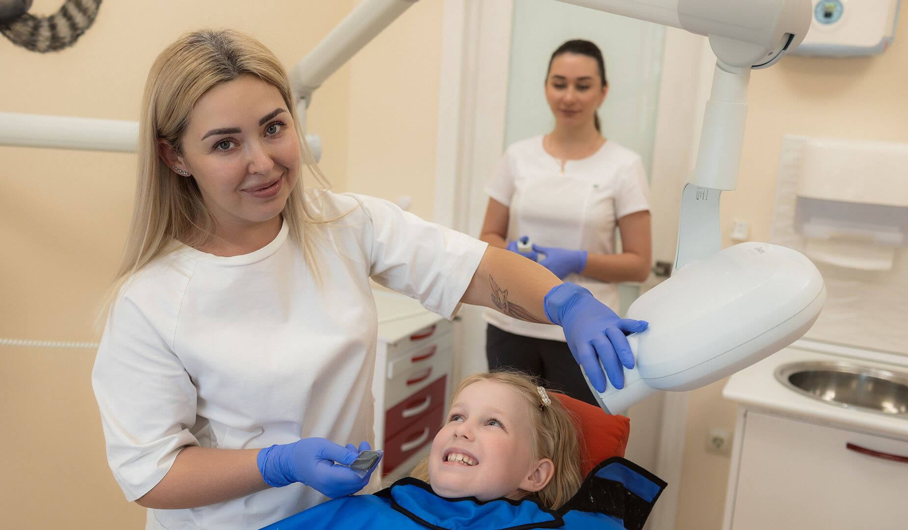 Осмотр маленькой пациентки в кресле у стоматолога