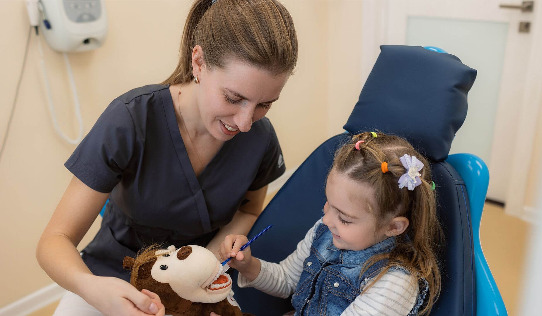 Осмотр маленькой пациентки в кресле у стоматолога